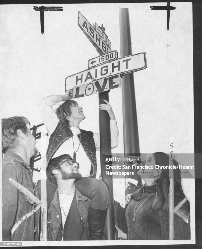 Sharon Sweeney, Larrry Sweeney and Beth Barton tape a Love sign with the Haight-Ashbury street sign. ;150 Anniversary maybe
