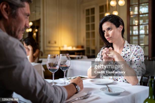 disbelieving wife listening to her husband lying at dinner - couple relationship difficulties stock pictures, royalty-free photos & images