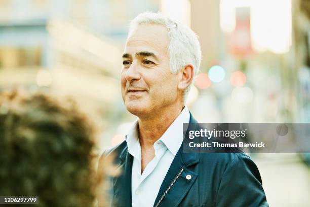 Smiling senior businessman in discussion with colleague on city street