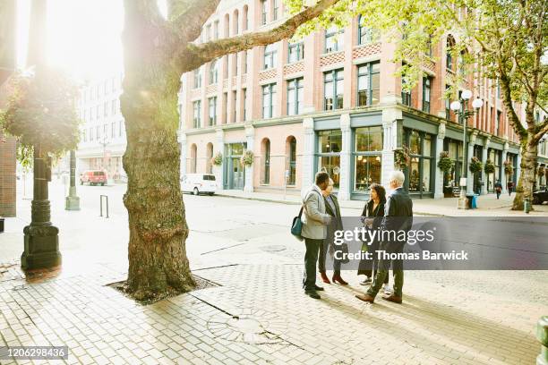 business colleagues in discussion on city street during morning commute - day in the life usa stock-fotos und bilder