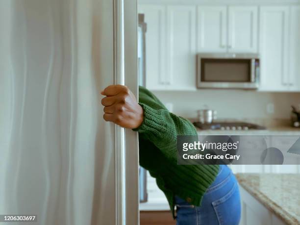 woman looks into refrigerator for healthy snack - appetite stock pictures, royalty-free photos & images