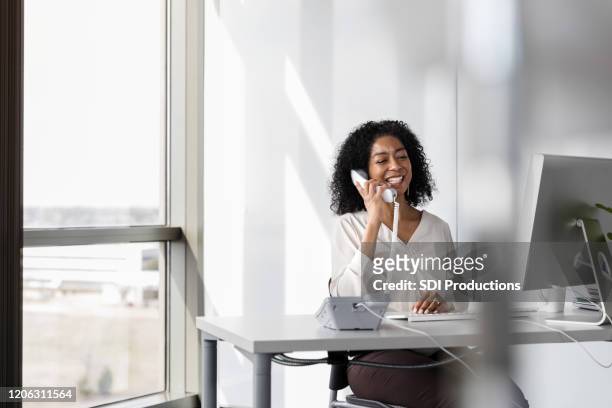 businesswoman uses phone in her office - landline phone stock pictures, royalty-free photos & images