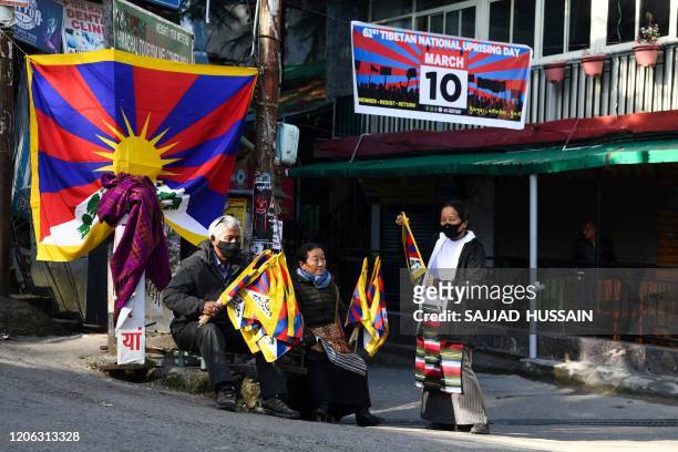 Tibetans living in exile hold flags as they wait to join an event to mark the 61st anniversary of the Tibetan Uprising Day that commemorates the 1959...