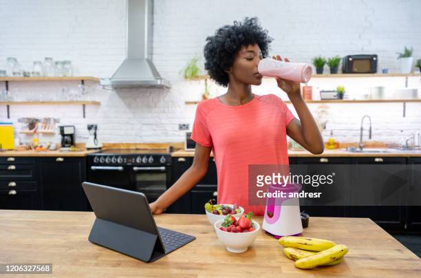 afrikaanse amerikaanse vrouw thuis die een smoothie drinkt - smoothie and woman stockfoto's en -beelden