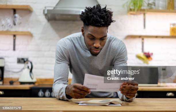 black man at home reading the mail - reading mail stock pictures, royalty-free photos & images