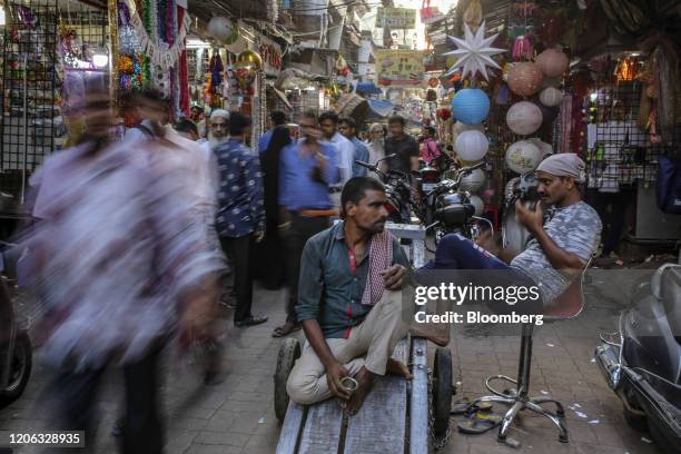 Pedestrians and shoppers walk past stores near Crawford market in Mumbai, India, on Monday, March 9, 2020. India's central bank seizing control of...