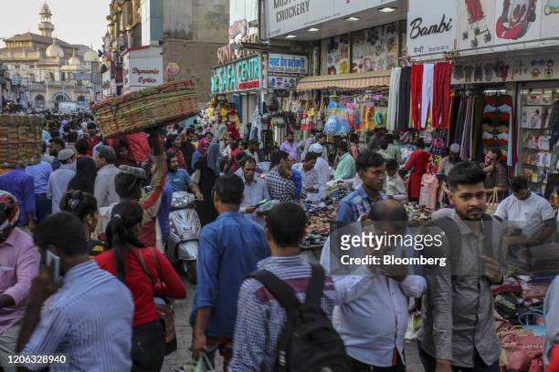 Pedestrians and shoppers walk past stores near Crawford market in Mumbai, India, on Monday, March 9, 2020. India's central bank seizing control of...