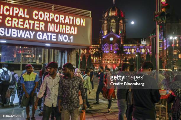Pedestrians walk past an entrance to the CST Underground Metro Station near the Chhatrapati Shivaji Terminus railway station illuminated at night in...