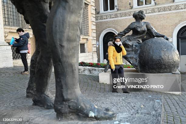 People, some wearing a respiratory mask, stand at the entrance of the Provincia prefecture building in downtown Rome on March 10, 2020. - Italy...