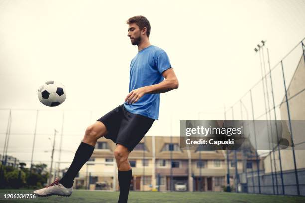 young man ball juggling with her feet at soccer field - malabarismo imagens e fotografias de stock