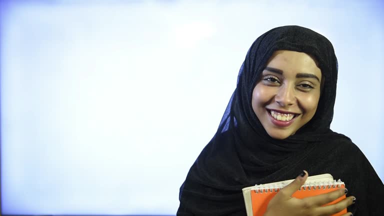 https://media.gettyimages.com/id/1206348998/video/muslim-girl-wearing-hijab-hugs-orange-book-and-smiling.jpg?b=1&s=640x640&k=20&c=rYa2ZbmbBv8xW8Md2bRAACte6F-FTrR-1Uhdwk6Rv2w=