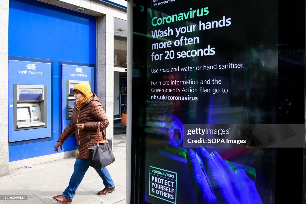 A woman walks past a Coronavirus public information campaign...