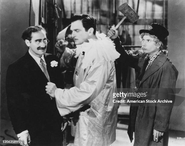 American actor Walter Woolf King threatens Groucho Marx , unaware of Harpo Marx , who is behind him with a mallet raised, in a scene from 'A Night At...