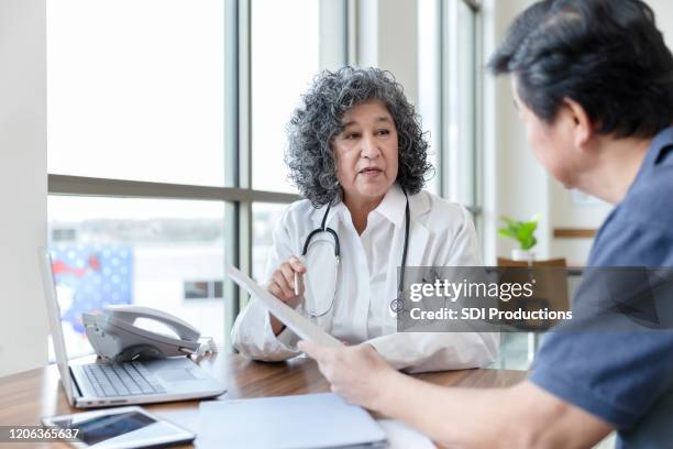 serious doctor talks with patient about a medical document - stern form stock pictures, royalty-free photos & images