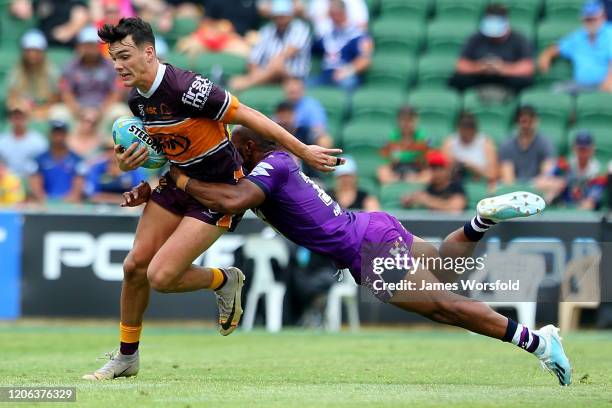 Herbie Farnworth of the Broncos tries to escape the diving tackle of Justin Olam of the Storm during the match between the Broncos and Storm from Day...