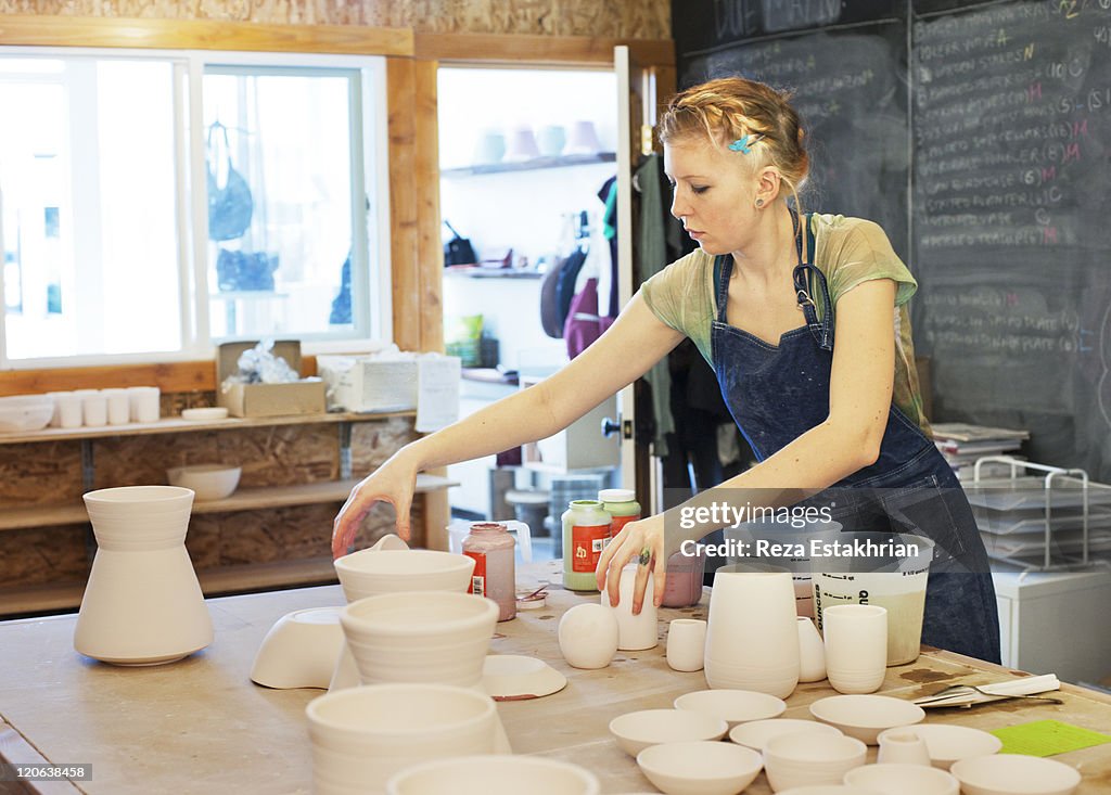 Woman places color on unglazed pottery