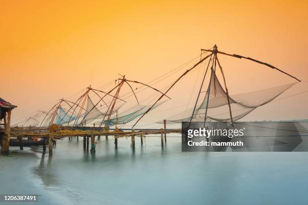 filets de pêche chinois traditionnels à kochi, inde au lever du soleil - kochi india photos et images de collection