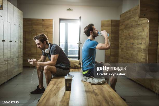 young athletic men sitting at gym's locker room. - mens changing room stock pictures, royalty-free photos & images