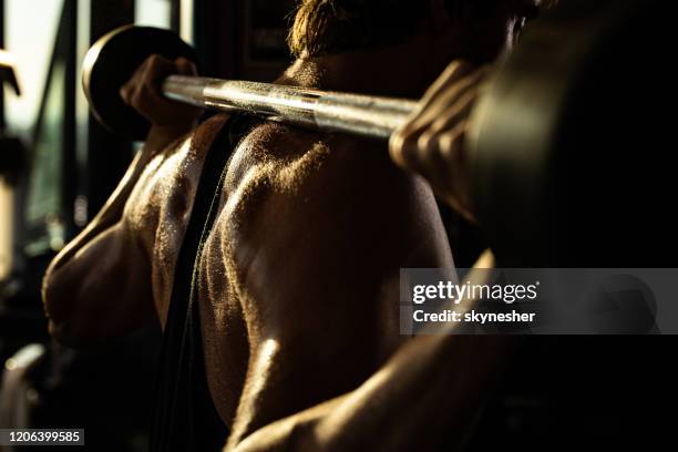 close up of sweaty sportsman doing back exercises with barbell in a gym. - back detail stock pictures, royalty-free photos & images