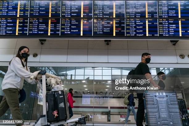 Travellers wearing masks walk at the arrival hall of the Hong Kong International Airport on March 10, 2020 in Hong Kong, China. Hong Kong's...