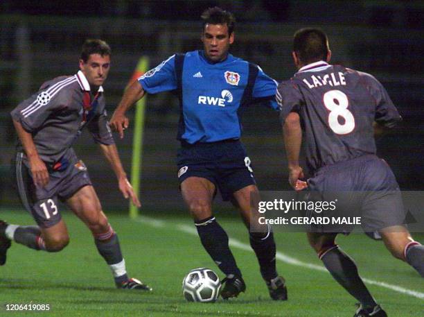 Le milieu de terrain lyonnais Pierre Laigle , épaulé par son coéquipier le défenseur Jérémie Brechet , tente de stopper le défenseur de Leverkusen...