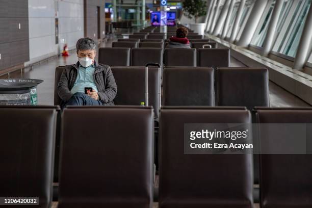 Traveler is seen wearing a facemask to protect himself from COVID-19 while waiting for his flight inside Incheon International Airport on March 10,...