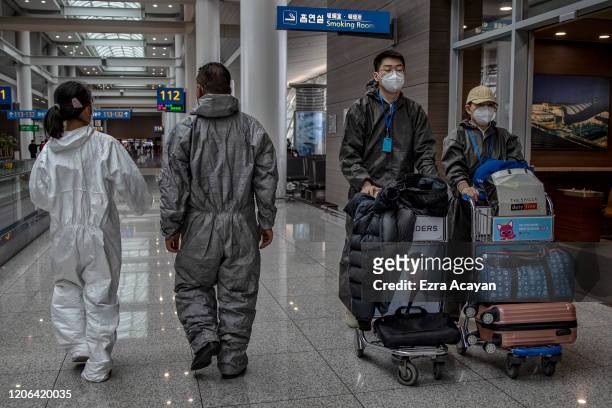 Travelers are seen wearing rain suits and facemasks to protect themselves from COVID-19 while waiting for their flight inside Incheon International...