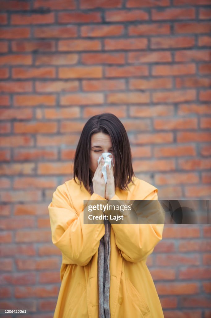 Sick woman blowing her nose at street