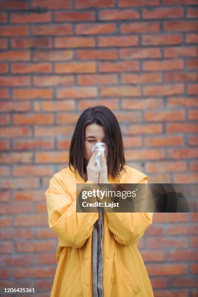 sick woman blowing her nose at street - sistema imunológico humano imagens e fotografias de stock