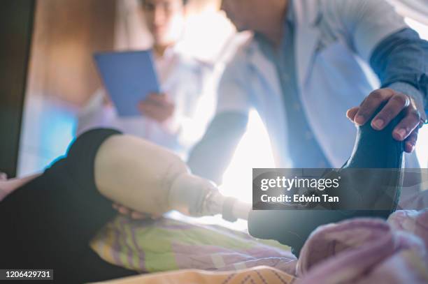 2 médicos asiáticos chinos y malayos discuten y visitan a la paciente india con pierna protésica en el pabellón del hospital sobre su recuperación - equipo protésico fotografías e imágenes de stock