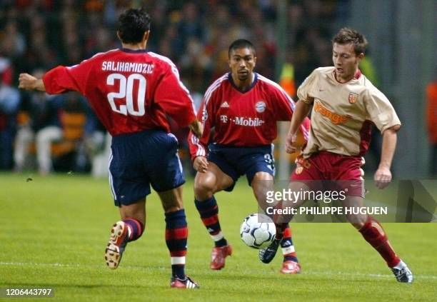L'attaquant de Lens Jacek Bak est à la lutte avec les joueurs du Bayern de Munich, le défenseur Elber Giovani et le joueur Hasan Salihamidzic, le 24...