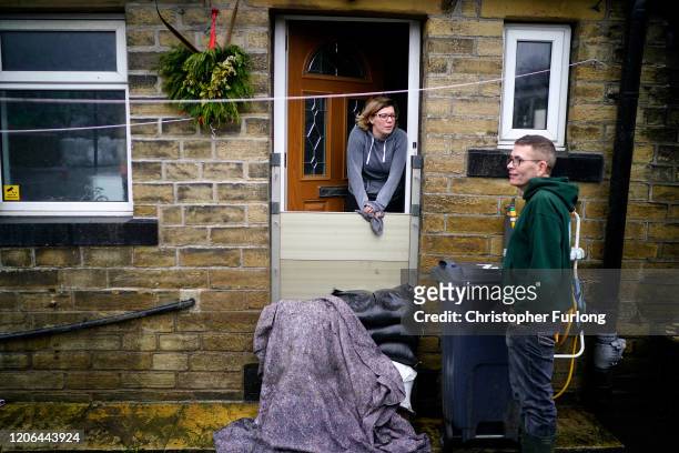 Mytholmroyd residents look out over the flood defences as soldiers arrive to help shore up flood barriers and Storm Dennis begins to make landfall in...