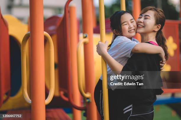 una madre china asiática jugando y divirtiéndose con su hija en el patio de recreo - fond orange fotografías e imágenes de stock