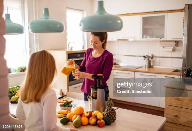 woman preparing cold pressed juice to her daughter - avocado smoothie stock pictures, royalty-free photos & images