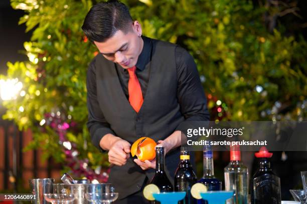 asian male bartender in black formal suit  mixing cocktail drinks  outdoors at night. - cocktail counter stock pictures, royalty-free photos & images