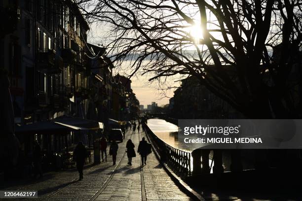 View shows people strolling along a canal in the Navigli district of Milan on March 10, 2020 as Italy imposed unprecedented national restrictions on...