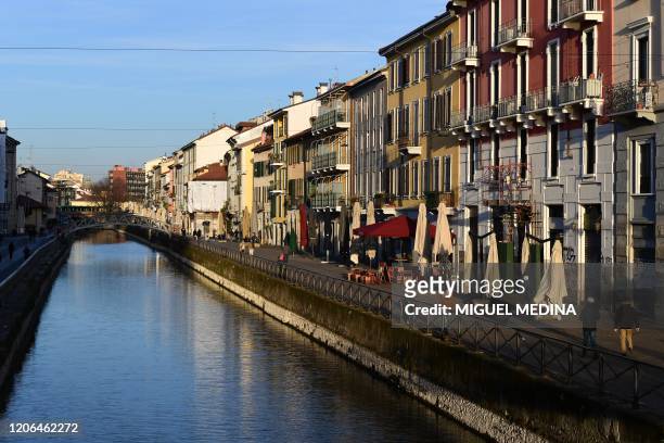View shows people strolling along a canal as the sun sets over the Navigli district of Milan on March 10, 2020 as Italy imposed unprecedented...