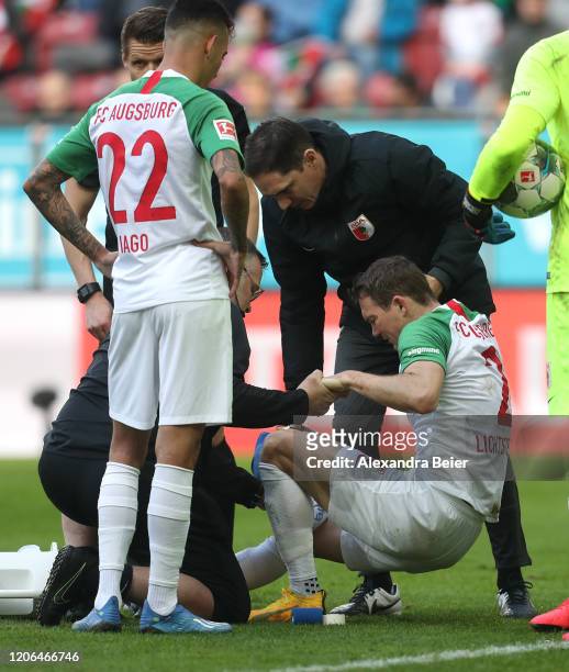 Stephan Lichtsteiner of FC Augsburg is treated by the medical team on the pitch after he was injured during the Bundesliga match between FC Augsburg...