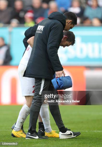 Stephan Lichtsteiner of FC Augsburg walks off the pitch held by the medical team after he was injured during the Bundesliga match between FC Augsburg...