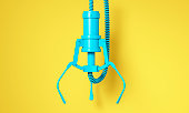 Blue robotic claw on yellow background and space for text