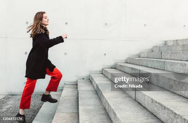 frau klettert die treppe hinauf - treppenhaus stock-fotos und bilder