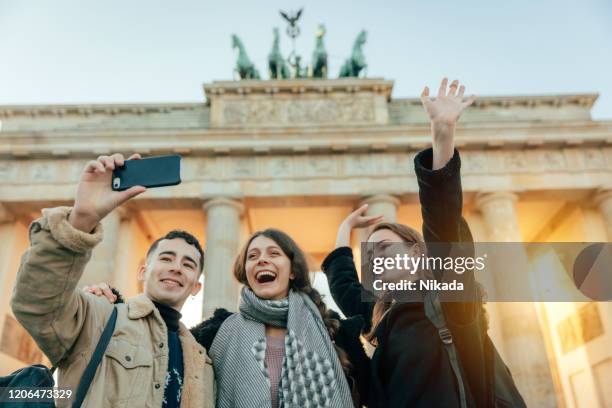 happy friends at brandeburg gate in berlin take a selfie - brandenburg stock pictures, royalty-free photos & images