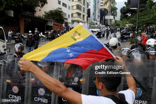 An anti-Maduro demonstrator waves a Venezuelan flag in front of the Venezuelan National Police officers during a demonstration against the government...