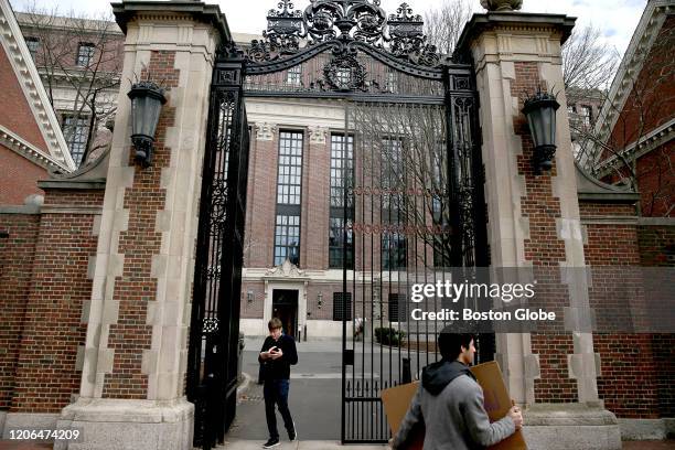 Person walks through Harvard University's campus with a box in Cambridge, MA on March 10, 2020. All Harvard courses will move to remote instruction...
