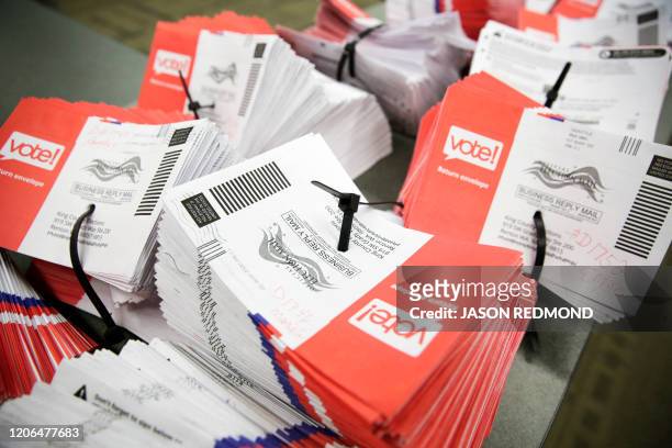 Empty envelopes of opened vote-by-mail ballots for the presidential primary are stacked on a table at King County Elections in Renton, Washington on...
