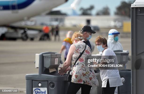 Medical Personnel help passengers from the Grand Princess cruise ship prepare to board airplanes at Oakland International Airport in Oakland,...