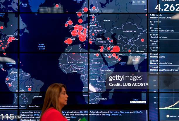 Woman passes by a world map showing countries infected with the new Coronavirus, COVID-19, during a press conference at the National Police...