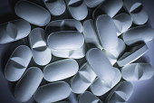Closeup of many prescription drugs, medicine tablets or vitamin pills in a pile with cool blue color tone - Concept of healthcare, opioids addiction, medicament abuse or medication treatment