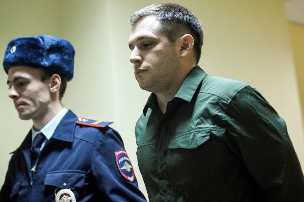 Police officers escort US ex-marine Trevor Reed, charged with attacking police, into a courtroom prior to a hearing in Moscow on March 11, 2020.