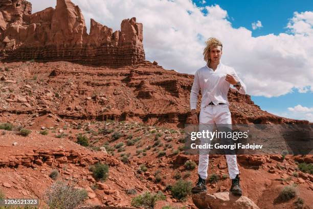 a curly haired blonde man posing around the famous buttes of monument valley from arizona, usa, wearing white linen shirt and white pants, black shoes, majestic beauty. - cowboy models stock-fotos und bilder